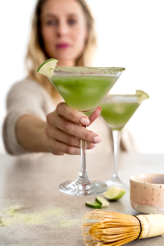Ein Glas mit einem Matcha Drink wird ins Bild gehalten